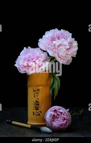 Pivoine chinoise (Paeonia lactiflora) en vase de bambou et pinceau de calligraphie, pinceau à encre Banque D'Images