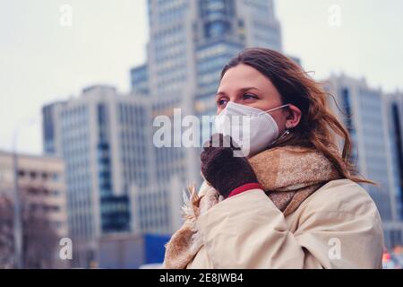 Portrait d'une femme adulte aux cheveux bouclés portant un respirateur ffp2 sur la rue de la ville Banque D'Images