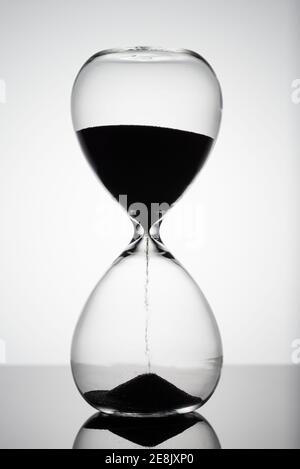 Le sable se déplace à travers le sablier. Gros plan de l'horloge en verre. Minuterie en verre de sable classique de l'ancien temps. HourGlass comme concept de dépassement de temps pour les délais d'affaires, Banque D'Images