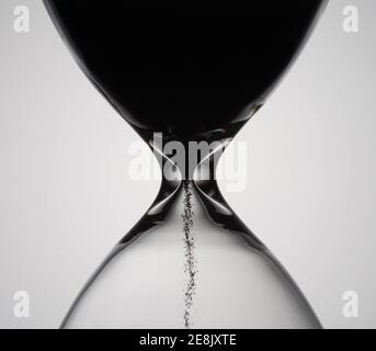 Le sable se déplace à travers le sablier. Gros plan de l'horloge en verre. Minuterie en verre de sable classique de l'ancien temps. HourGlass comme concept de dépassement de temps pour les délais d'affaires, Banque D'Images