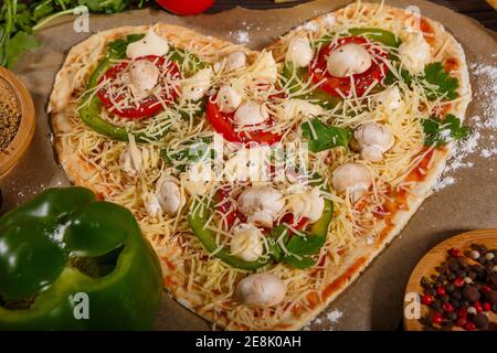 Pizza avant cuisson, légumes et épices sur fond de bois sombre Banque D'Images
