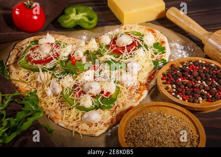 Pizza avant cuisson, légumes et épices sur fond de bois sombre Banque D'Images