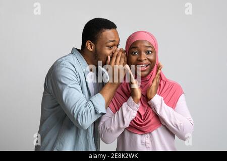 Un homme noir partageant la rumeur avec sa petite amie excitée Banque D'Images