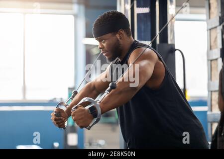 Jeune sportif noir entrainement triceps sur bloc exercice dans la salle de gym Banque D'Images