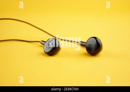 casque noir sur fond jaune. mise au point douce. gros plan. concept musical. simple Banque D'Images