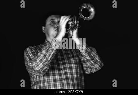 Portrait noir et blanc de trompettiste mature jouant l'instrument sur une scène. Banque D'Images