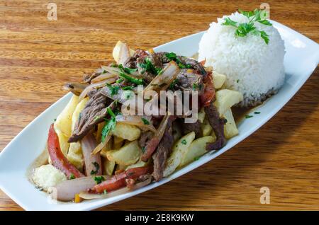 Plat appelé péruvienne Lomo Saltado faite de viande de boeuf, de tomates et oignons mélangés avec frites et servies avec du riz Banque D'Images