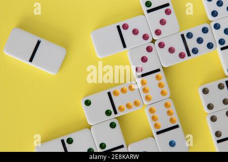 Dominos colorés disposés sur fond jaune Banque D'Images