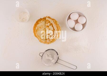 fines crêpes rondes avec œufs de poulet et farine sur blanc assiette frite Banque D'Images