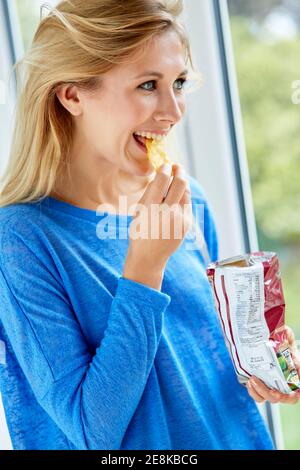 Fille mangeant un sac de chips Banque D'Images