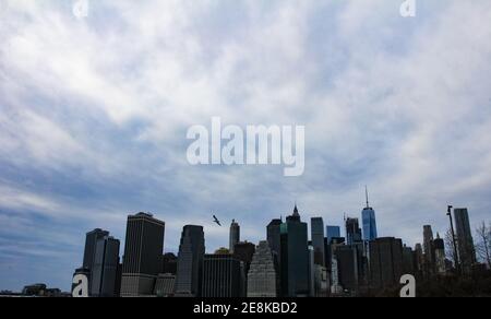 Vue sur les gratte-ciel de Lower Manhattan depuis la promenade des hauteurs de brooklyn avec ciel nuageux météo et oiseaux volants Banque D'Images