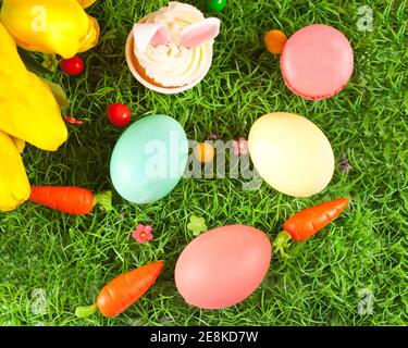 Quatre oeufs de Pâques décorés dans l'herbe avec des fleurs tulipes. Vue de dessus Banque D'Images