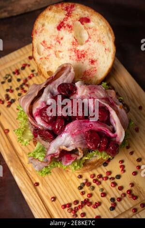 Hamburger artisanal créatif avec tranches de bacon frites et sauce aigre-douce et cerise sur le dessus, laitue fraîche avec pain de plomb à côté. Restaurant Banque D'Images