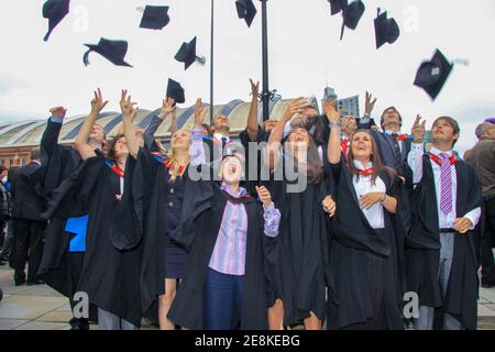 Des étudiants récemment diplômés lancent leur chapeau de mortier dans l'air dans la célébration à obtenir leurs diplômes Banque D'Images