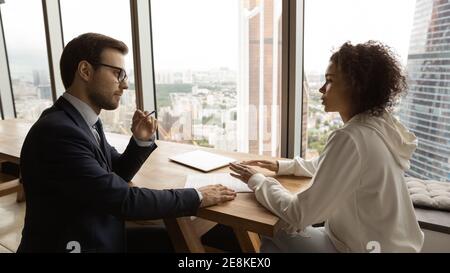 Homme confiant consultant parlant avec une femme africaine au bureau Banque D'Images