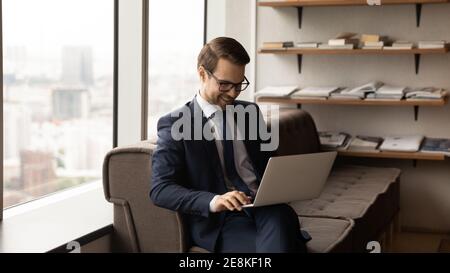 Un jeune cadre heureux travaille sur un pc au sein du réseau d'entreprise Banque D'Images