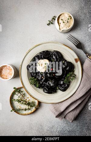 Assiette de pelmeni, raviolis ou boulettes russes traditionnels sur fond noir, vue de dessus Banque D'Images