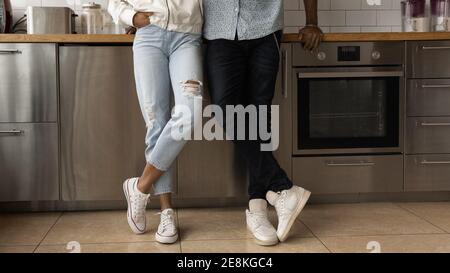 Jeune couple noir posant à l'intérieur croisant les jambes dans des chaussures de sport Banque D'Images