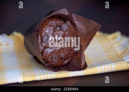 muffins au chocolat dans des tasses en papier brun sur une planche à découper en bois Banque D'Images