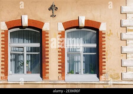 Deux fenêtres voûtées sur le fond d'un mur rose encadré de briques rouges. De la fenêtre de la série mondiale. Banque D'Images