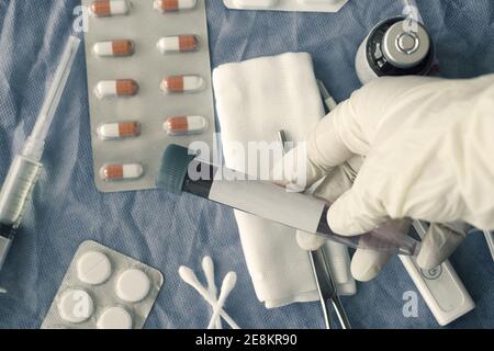 Un gros plan d'une te de sang dans la main d'un médecin sur un arrière-plan de la table d'opération Banque D'Images