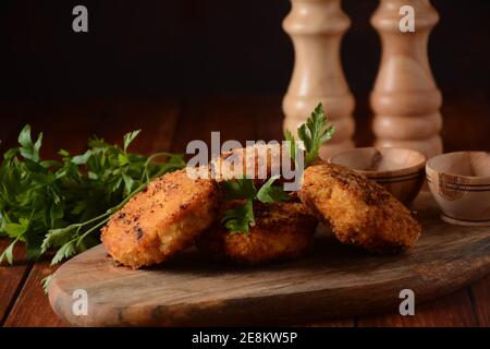 Côtelettes de poulet maison, frites juteuses. Enrobé de chapelure, délicieux, sur un vieux bois sombre, style rustique, avec des épices et des herbes. Banque D'Images