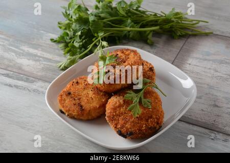 Côtelettes de poulet maison, frites juteuses. Enrobé de chapelure, délicieux, dans un plat blanc aux herbes. Sur fond de bois ancien, style rustique Banque D'Images