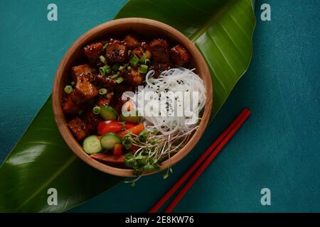 Tofu frit avec des nouilles de cristal de riz dans un bol en bois. Banque D'Images