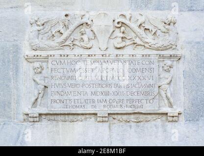 Inscription latine ornée de figures mythologiques sculptées en pierre sur la façade de la cathédrale de Côme.Lombardie, Italie. Banque D'Images