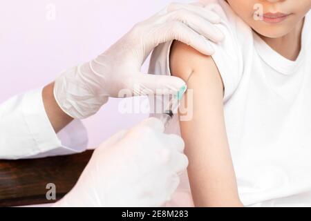 Un enfant heureux est vacciné. Médecin vaccinant le petit garçon. Médecin examinant un enfant à l'hôpital. Banque D'Images