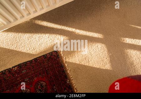 Formes et ombres avec fragments d'un radiateur de chauffage central, tapis de laine, tapis persan et une éclaboussure de rouge dans une maison anglaise Banque D'Images