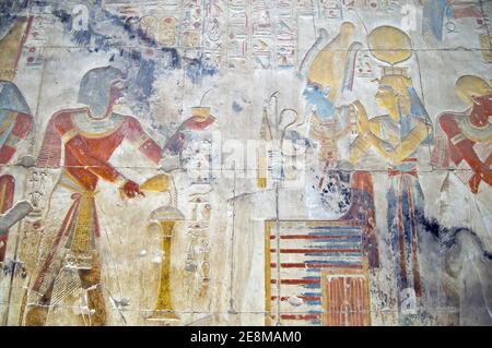 Sculpture égyptienne antique montrant le Pharaon Seti I faisant une offrande au dieu du monde inférieur Osiris avec la déesse Isis. Mur du temple Banque D'Images