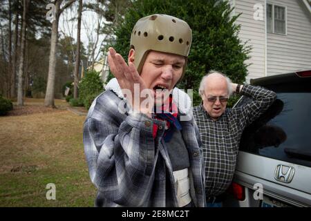 Jonesboro, GA, États-Unis. 31 janvier 2021. Tim McBroom montre sa frustration lors d'une promenade avec son père Mike McBroom à l'extérieur de leur maison. Mike et Sheila McBroom sont souvent éveillés la nuit, remplis d'anxiété au sujet de leur fils adultes handicapés, Tim's future. Tim, 36 ans, qui est non verbal et connaît un autisme grave, a des crises et des problèmes de comportement. McBroom et sa femme font de leur mieux pour offrir à leur fils un environnement sûr et sécuritaire dans leur maison de Jonesboro, avec l'aide quotidienne du personnel de soutien financé par Medicaid. Mais les réductions proposées à ces services financés par Medicaid tournent le dos Banque D'Images