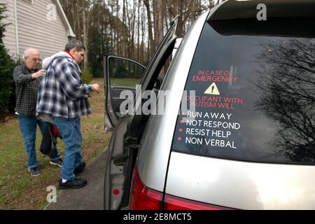 Jonesboro, GA, États-Unis. 31 janvier 2021. Mike McBroom aide son fils handicapé Tim dans la camionnette familiale pour un trajet vers un restaurant local. La fourgonnette est clairement marquée d'un avertissement d'urgence indiquant qu'un occupant est autiste et non verbal.Mike et Sheila McBroom se trouvent souvent éveillés la nuit, remplis d'anxiété au sujet de leur fils adultes handicapés Tim's future. Tim, 36 ans, qui est non verbal et connaît un autisme grave, a des crises et des problèmes de comportement. McBroom et sa femme font de leur mieux pour offrir à leur fils un environnement sûr et sécuritaire dans leur maison de Jonesboro, avec l'aide quotidienne de Medicaid WIV Banque D'Images