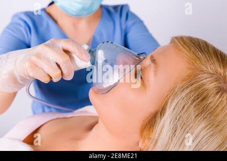 Photo agrandie. Un médecin portant un uniforme médical tient un masque nébuliseur pour une femme âgée sur fond blanc. Diagnostic médical du coronavirus Banque D'Images