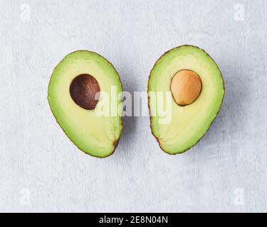 Deux moitié avocat avec graines sur fond de table en béton gris. Banque D'Images