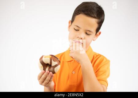 le garçon de l'adolescence avec des beignes pense à la collation de sucre que rend son enfance joyeuse et douce Banque D'Images