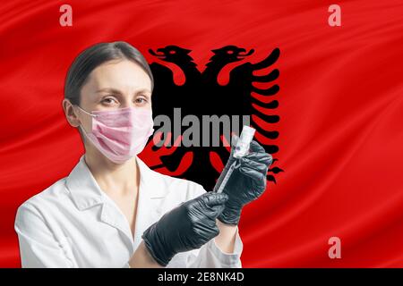 La jeune fille prépare la vaccination contre le fond du drapeau de l'Albanie. Concept de vaccination Albanie Banque D'Images