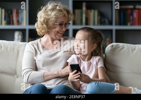 Heureux de lier une grand-mère ancienne et mature à l'aide d'un smartphone avec une petite-fille. Banque D'Images