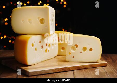 Fromage sur table sur fond sombre. Tête de fromage dure moyenne edam, gouda, parmesan sur bois. Concept de saine alimentation. Banque D'Images