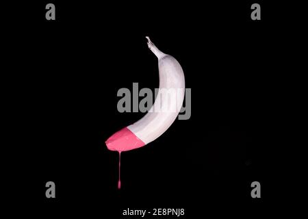 Banane flottante blanche avec peinture goutte d'eau rose. Arrière-plan noir. Concept alimentaire créatif Banque D'Images