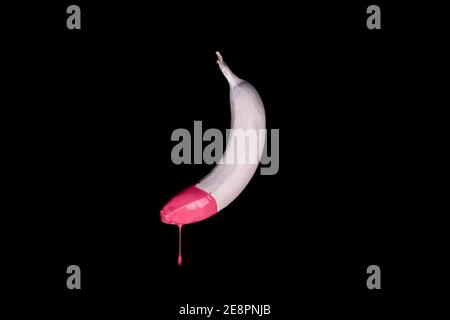 Banane flottante blanche avec peinture goutte d'eau rose. Arrière-plan noir. Concept alimentaire créatif Banque D'Images