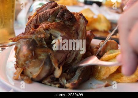 Manger un porte-jarret de porc rôti avec des frites Banque D'Images