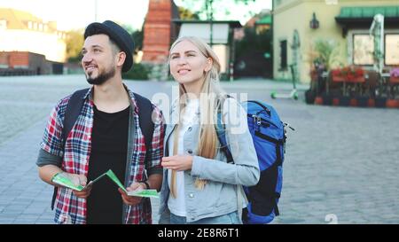 Un couple de touristes à la mode qui trouvent la destination nécessaire sur la carte et qui admirent les environs. Ils se tiennent sur la place de la ville. Banque D'Images