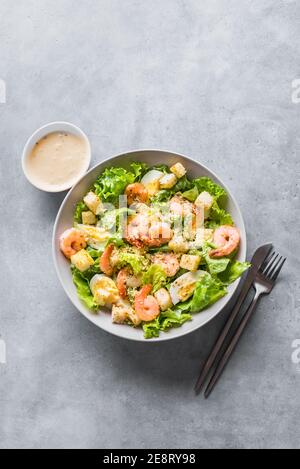 Salade de crevettes. Salade César aux fruits de mer servie avec une sauce césar et du parmesan sur fond gris, vue du dessus, espace de photocopie. Banque D'Images