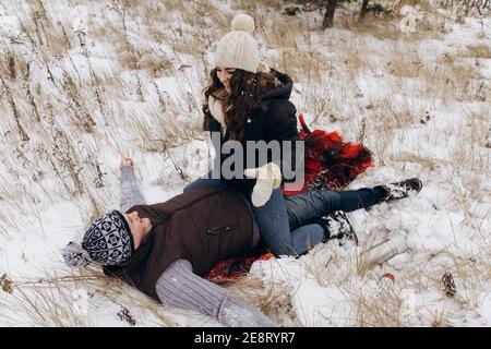 La femme est assise sur l'homme. L'homme est dans la neige. Banque D'Images