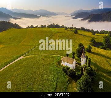 Cerkev Marijinega, Slovénie - vue aérienne de l'église de Marie (Cerkev Marijinega) le matin d'été ensoleillé avec les alpes slovènes et l'église de St au sommet d'une colline Banque D'Images