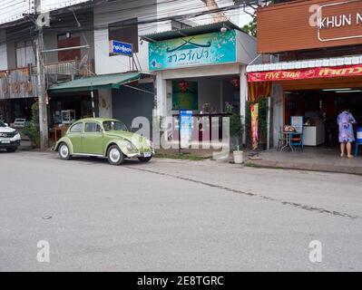 Un coléoptère vert volkswagen est stationné sur le côté de la route en face de la boutique Banque D'Images