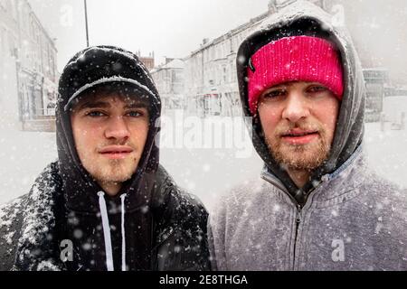 Deux frères regardent la caméra dans une tempête de neige Banque D'Images