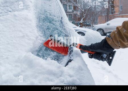 Main avec une brosse pour nettoyer le pare-brise de la voiture de la neige. Conduite en hiver Banque D'Images